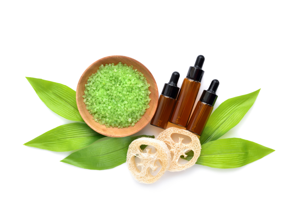 Organic spa cosmetic - bath salt, bottles of essential oils and green leaves